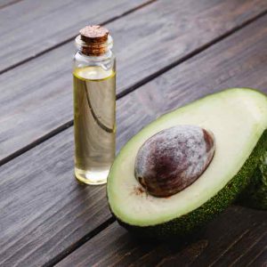 Little bottle with oil and avocado stand on the wooden table
